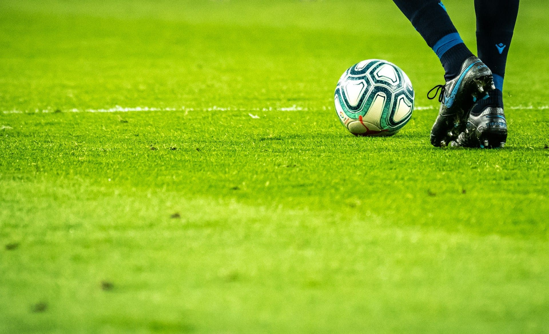 Footballer dribbling a match ball on the pitch